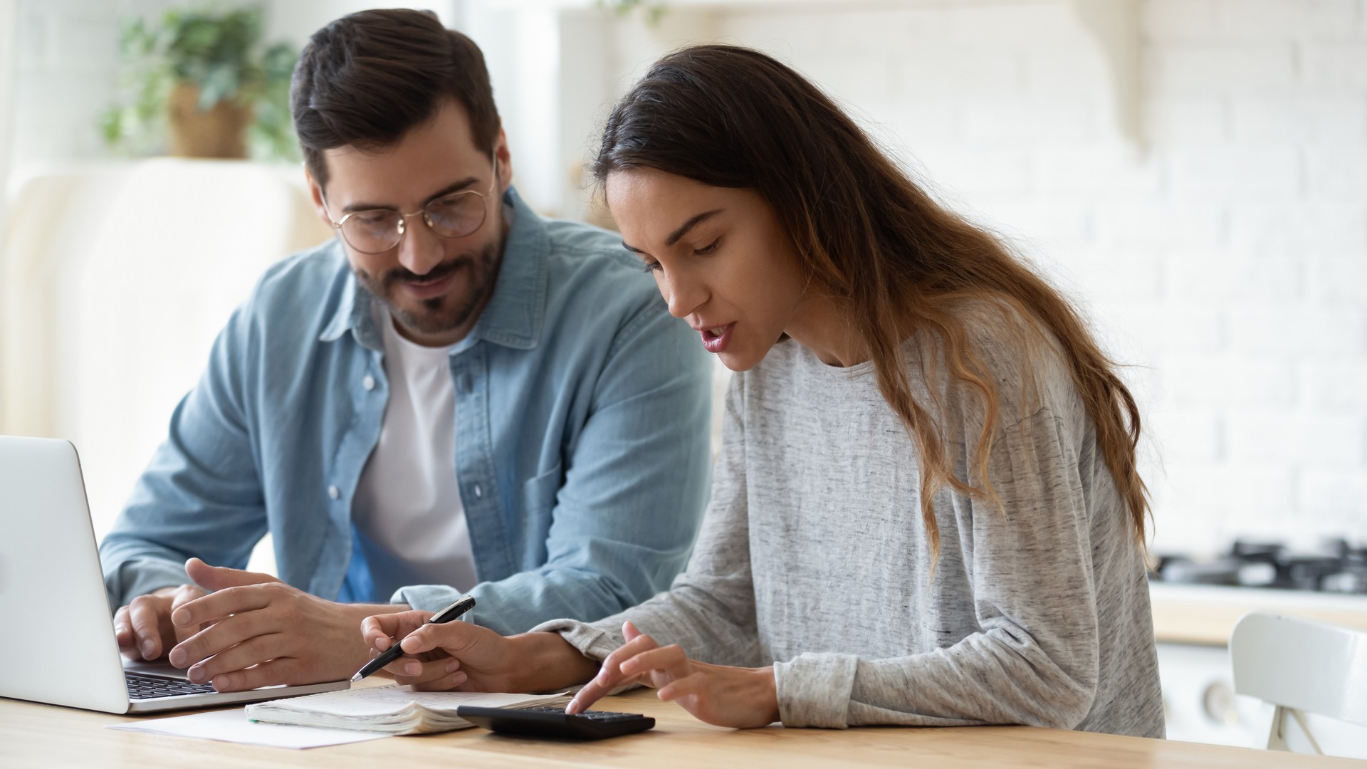 Marido e esposa novos que usam o portátil da calculadora que fala que faz o documento